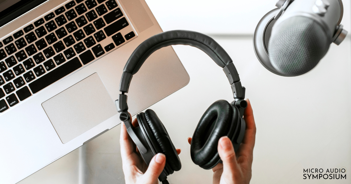 Eine Person hält schwarze Kopfhörer über einem Laptop, daneben ein Mikrofon – perfekt für die Aufnahme eines privaten Podcasts. Unten rechts erscheint der Schriftzug „Micro Audio Symposium“.
