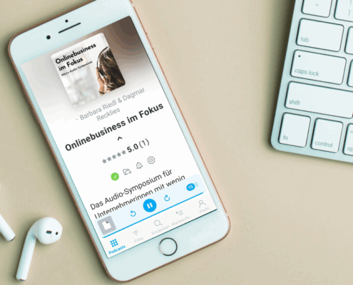 Ein Smartphone auf einer grünen Fläche zeigt das Hörbuch "Onlinebusiness im Fokus" an. In der Nähe befinden sich kabellose Ohrstöpsel, ein Teil einer kabellosen Tastatur und der Text "MICRO AUDIO SYMPOSIUM", der diesen Audio-Leitmagneten in Aktion zeigt.