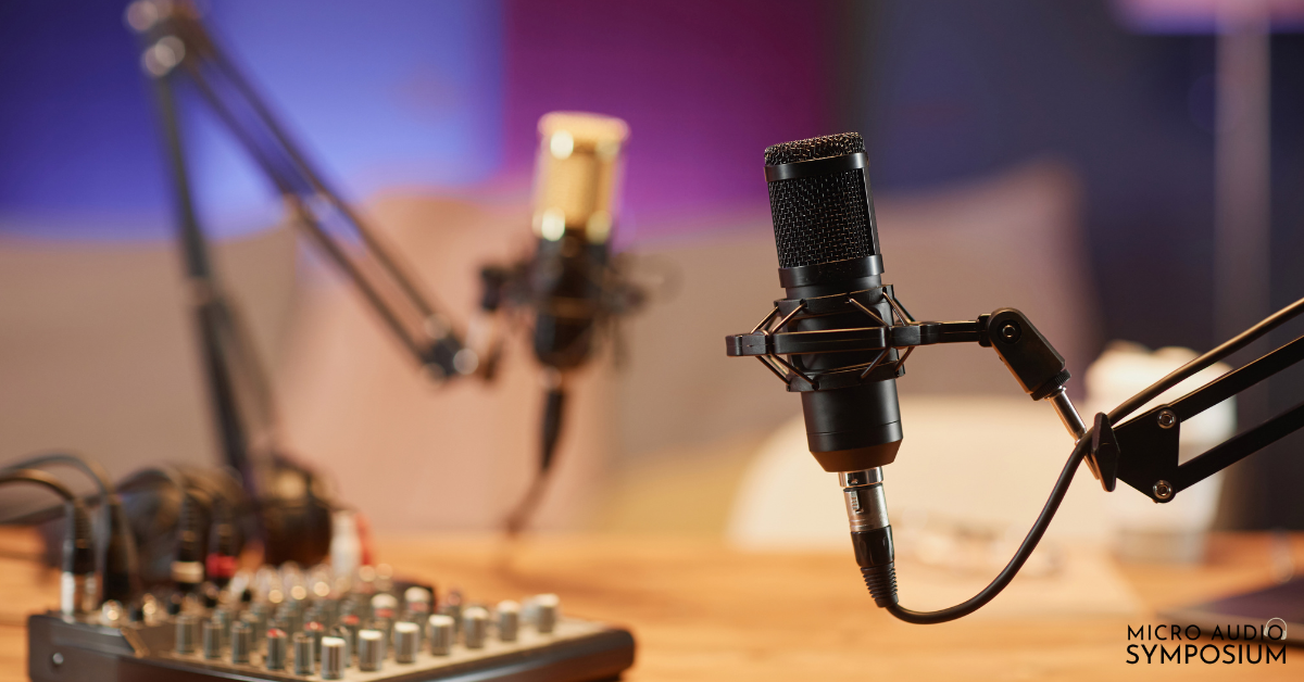 Zwei Mikrofone an Galgenarmen und ein Mischpult auf einem Holztisch, bereit für Podcast-Interviews.